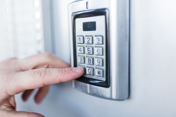 Close up of businessman hand entering security system code.