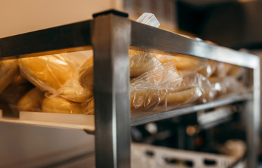 Buns for burgers in white drawer on shelves in a polythene bag in the kitchen