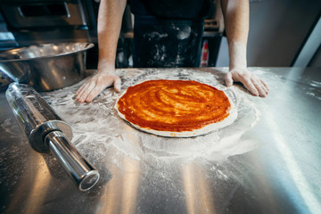 Chef starts to prepare pizza at a pizzeria