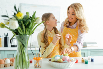 Selective focus of happy child holding easter egg and looking at mother