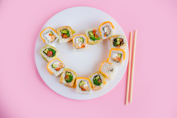 vegetarian sushi rolls on a white plate on a pink