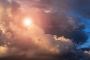 Dramatic epic storm sky with cumulus clouds, orange sun and sunlight, heaven