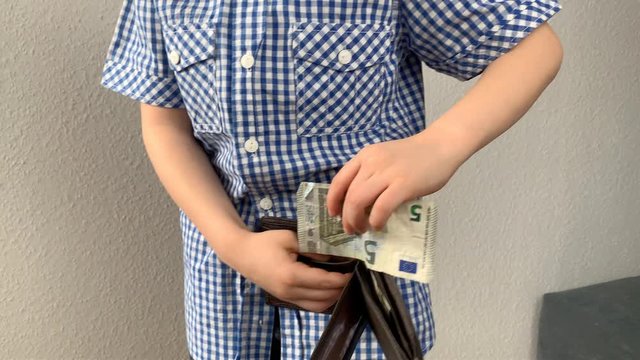 kid holds euro banknotes in his hand and puts them in a brown wallet, concept of pocket money, theft, shopping