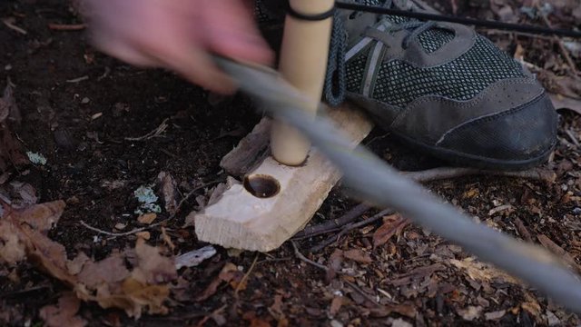 Making fire with bow drill, smoke with no fire, close up in daylight