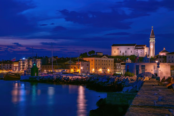 Picturesque nightscape of coastline of Adriatic sea with illuminated houses and lighthouse at...