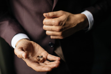 Close-up view of man's hands holding wedding rings.