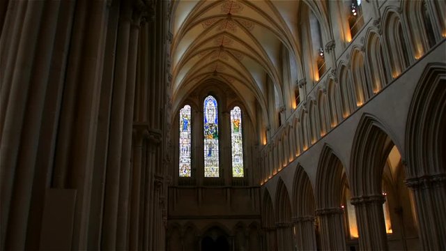 Stunning, smooth gliding shot looking down the spectacular nave towards the stained glass windows, inside Wells Cathedral, in Wells, England