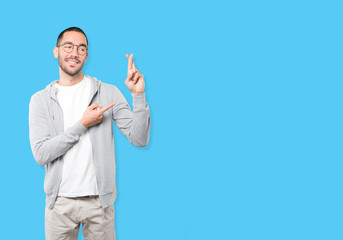 Happy young man doing a crossed fingers gesture