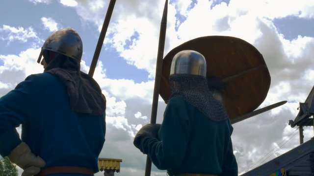 A group of knights in helmets mull over tactics before a battle