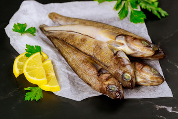 Whole fresh fish on parchment paper with lemon and parsley.
