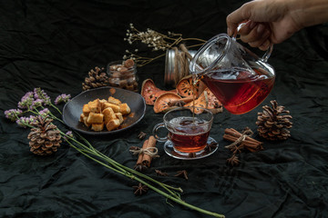 Bael fruit tea  is poured from a kettle into glass cup with bark of bael fruit.