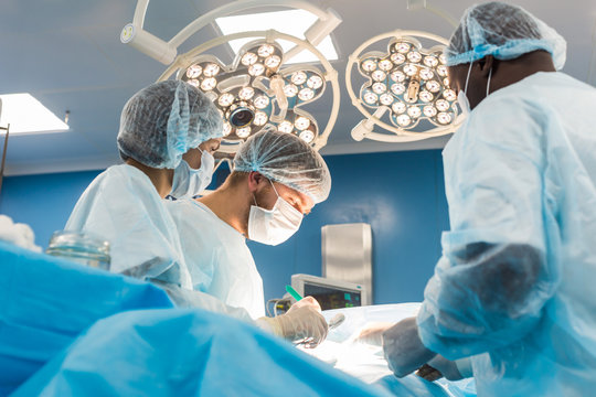 An international team of doctors performs a complex surgical operation on a patient under anesthesia. Modern operating room and experienced surgeons save lives