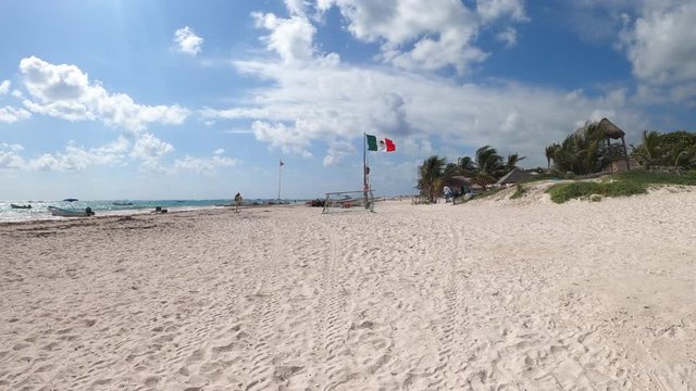 panoramic view of a Caribbean beach with white sand and flag on the background in Tulum Mexico