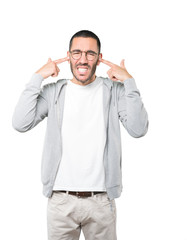 Concerned young man worried about loud noises and covering his ears