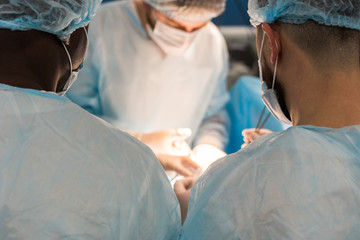 An international team of doctors performs a complex surgical operation on a patient under anesthesia. Modern operating room and experienced surgeons save lives