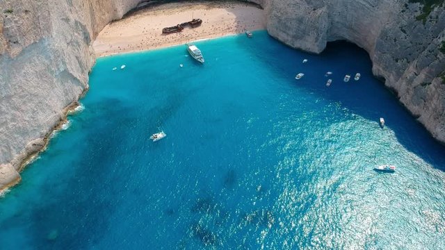 Navagio Beach, Zakynthos. Luxury summer vacation background. Secluded sandy beach with touristic boats and yachts floating in turquoise waters of the Ionian sea.