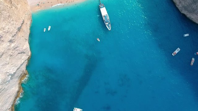 Tourist boats float near the hidden Zakynthos beach. Camera tilt down