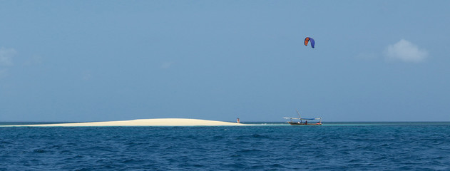 Kitesurfer and boat on Zanzibar virgin white sand beach