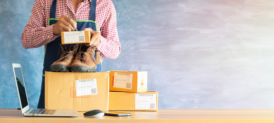 Laptop computer at workplace of start up, small business owner. cardboard parcel box of product for...