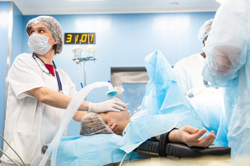 Portrait of an anesthesiologist among a team of doctors monitors instrument readings and patient status