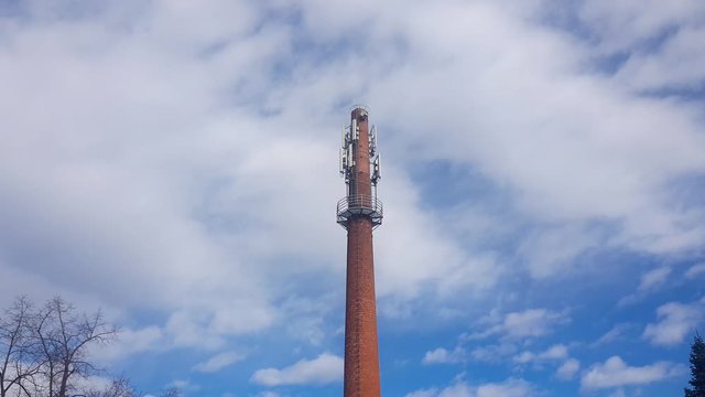Chimney with Mobile Telecom Antennas attached on top. Time lapse with moving Clouds in background.