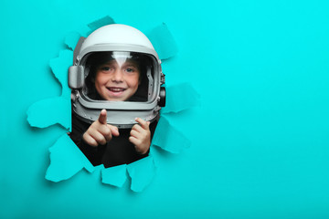Small child in wearing an airplane helmet looking through a hole of colored paper © vovan