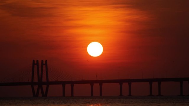 Sunset timelapse sun going behind a suspension bridge