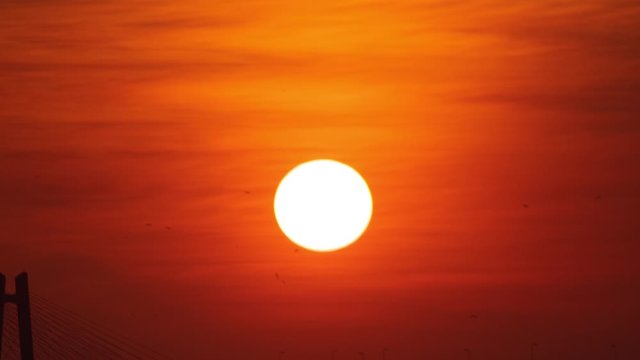 Timelapse of the sun setting behind a road bridge over the sea