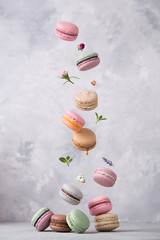 Sweet macaroons cookies falling in motion on grey background. Pastel colored flying macaroons with ingridients. Food, culinary and cooking concept levitation