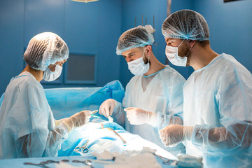 An international team of doctors performs a complex surgical operation on a patient under anesthesia. Modern operating room and experienced surgeons save lives