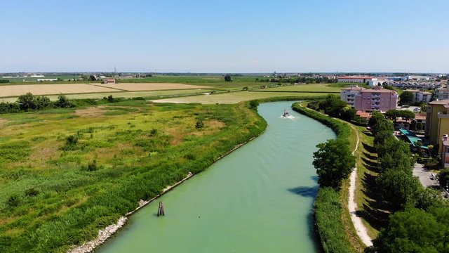 Boat on the Livenza River after entering through Porto Santa Margherita, Caorle Italy, Aerial drone flyover shot