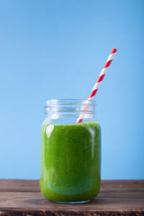 Fresh green smoothie on wooden and blue background. 