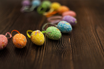 Colorful easter eggs close up on a dark wooden background. Side view, copy space for text and wording. Easter holidays concept and April vibes.