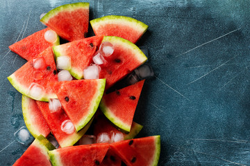Slices of fresh watermelon with ice on a blue concrete background. Detox and vegetarian concept. Top view, copy space, banner