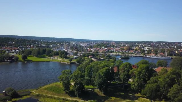 Aerial view revealing Tall Ship Race in Fredrikstad from behind trees with fortress town in foreground