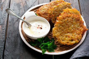 Draniki - potatof ritters, vegetarian potato pancakes, served with fresh herbs and garlic yogurt sauce, selective focus.