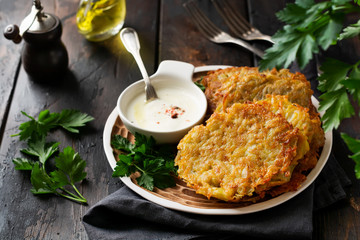 Draniki - potatof ritters, vegetarian potato pancakes, served with fresh herbs and garlic yogurt sauce, selective focus.