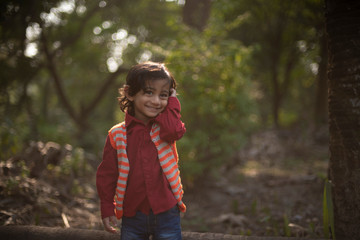 Portrait of an Indian brunette baby boy in winter wear enjoying himself in a field on a winter afternoon in green natural background. Indian lifestyle and childhood.