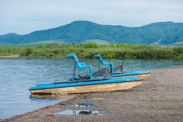Walking catamaran with pedals for riding on water in the background of high mountains.