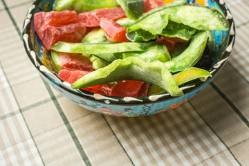 Pressed dried fruit from red papaya and green kiwi in deep plate on table.
