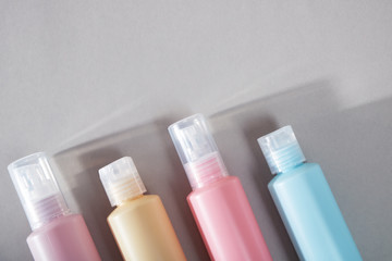 Travel kit. Set of four plastic bottles for cosmetic products. Gray background with shadows.