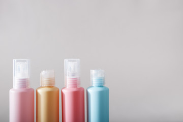 Travel kit. Set of four plastic bottles for cosmetic products. Gray background