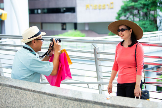 Travel and tourism concept. senior Asian couple with camera and take a photographing in the city with shopping paper bag