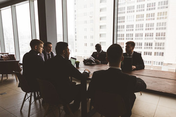 Silhouettes of people sitting at the table. A team of young businessmen working and communicating together in an office. Corporate businessteam and manager in a meeting.