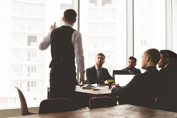 Silhouettes of people sitting at the table. A team of young businessmen working and communicating together in an office. Corporate businessteam and manager in a meeting.