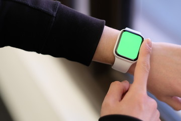 close up finger touch green screen electronic watch on wrist. Blur background 
