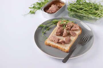 Healthy food, Sandwich with cod liver and peas microgrines on a plate on a white background