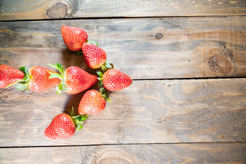  strawberry berries close up as an arrow pointer on a wood background
