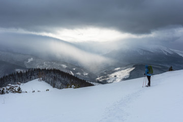 Well-equipped tourists, travel the winter ridges and enjoy the beauty of the surrounding mountains