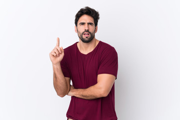 Fototapeta premium Young handsome man with beard over isolated white background thinking an idea pointing the finger up